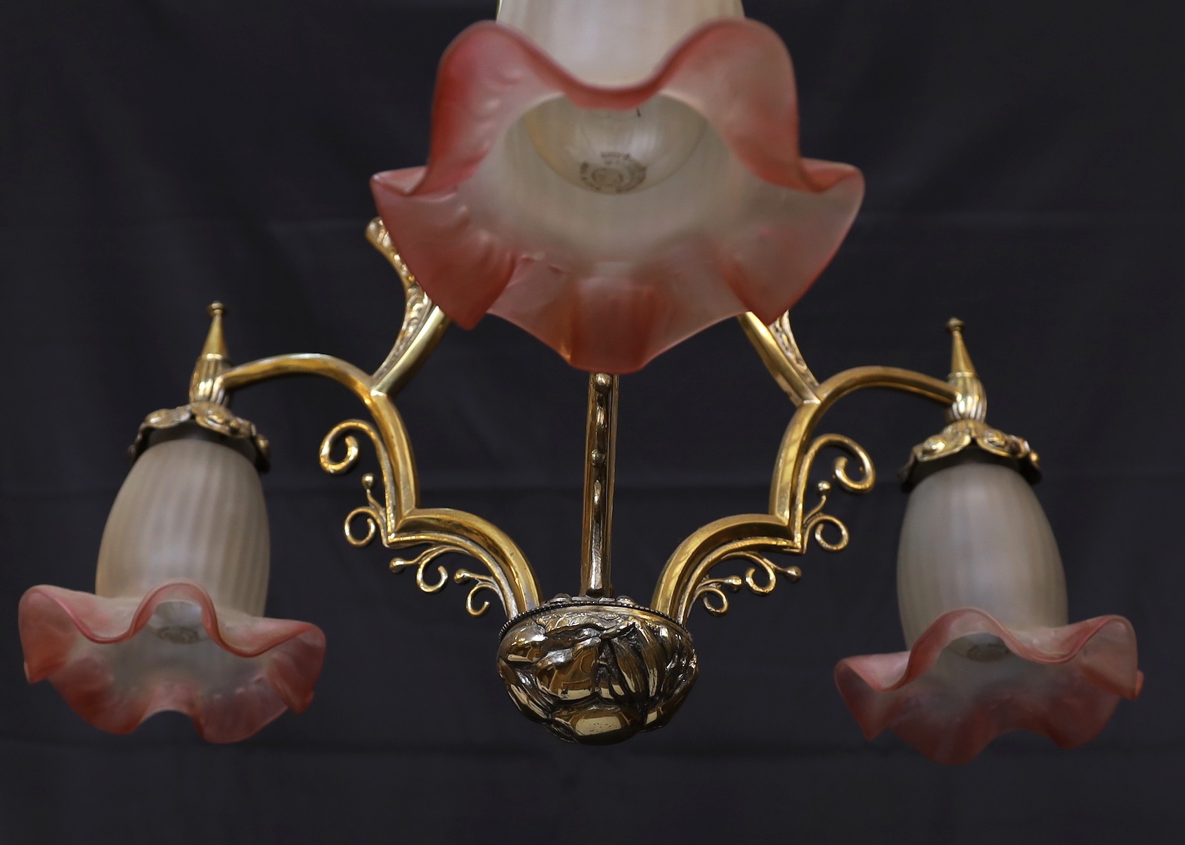 A 1930s French brass three light chandelier with cranberry tinted frosted glass shades, height 70cm. width 60cm